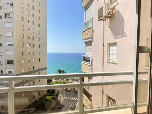 a view of the ocean from a balcony in a building at The Symphony of the Breeze in Netanya
