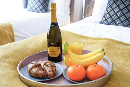 a bottle of wine and a plate of fruit and a bottle of orange juice at 3 Bedroom House in City Centre - Sleeps up to 7 - Free Parking, Fast Wifi, Pool Table and SmartTV with SkyTV and Netflix by Yoko Property in Northampton