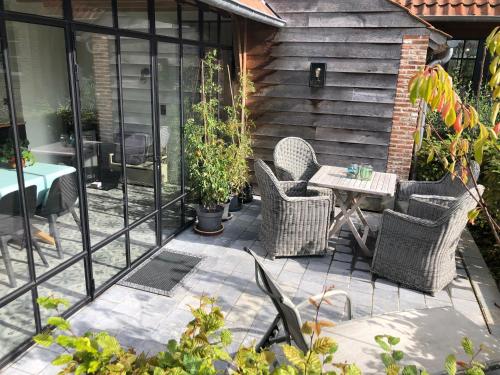 un patio al aire libre con sillas de mimbre y una mesa en Het mezennest en Zottegem