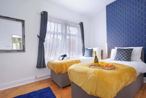 een slaapkamer met 2 bedden met gele lakens en een raam bij 3 Bedroom House in City Centre - Sleeps up to 7 - Free Parking, Fast Wifi, Pool Table and SmartTV with SkyTV and Netflix by Yoko Property in Northampton