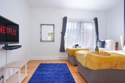 een woonkamer met 2 bedden en een blauw tapijt bij 3 Bedroom House in City Centre - Sleeps up to 7 - Free Parking, Fast Wifi, Pool Table and SmartTV with SkyTV and Netflix by Yoko Property in Northampton