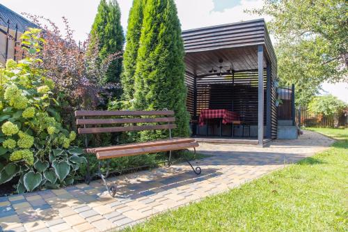 un banco de parque en un jardín con cenador en Seven en Vyshneve