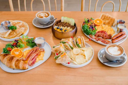 a table with plates of food and cups of coffee at Sleep Whale Hotel in Krabi town