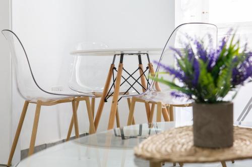 a glass table with chairs and a vase with purple flowers at Valletta Waterfront 2 Beds Flat by ArcoBnb in Il-Furjana