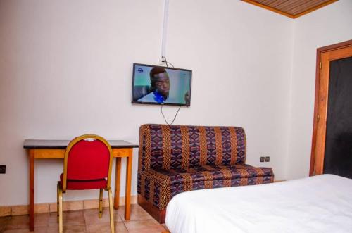 a bedroom with a bed and a chair and a tv on the wall at SUP HOTEL in Douala