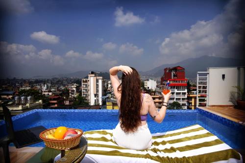 Divine Kathmandu Hotel في كاتماندو: امرأة تجلس على شرفة تمسك الجزر