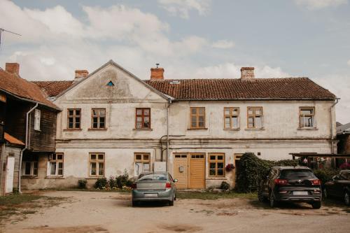 una gran casa blanca con dos coches aparcados frente a ella en Vītola apartamenti en Kuldīga