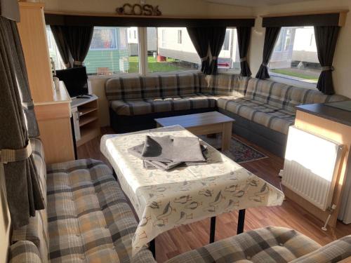 ein Wohnzimmer mit einem Sofa und einem Tisch in der Unterkunft 3 Bedroom Caravan - Maples 126, Trecco Bay in Newton
