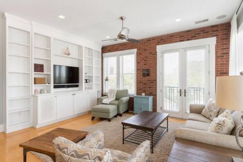 a living room with white furniture and a brick wall at Brooklyn Arts Condo in Wilmington