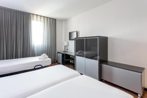 a hotel room with two beds and a desk at Hotel Ciudad de Móstoles in Móstoles