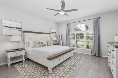 ein weißes Schlafzimmer mit einem Bett und einem Deckenventilator in der Unterkunft Villa Sunshine & Unwind - Cape Coral - Roelens Vacations in Cape Coral