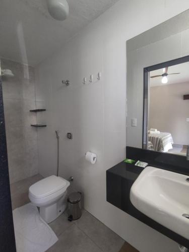 a bathroom with a toilet and a sink and a mirror at Vila da Praça Pousada in Capitólio