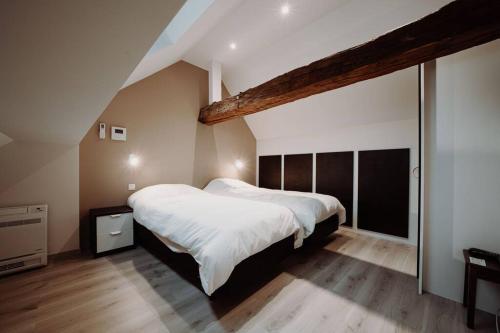 ein Schlafzimmer mit einem großen Bett mit weißer Bettwäsche in der Unterkunft Chimay : La Grande Réserve in Chimay