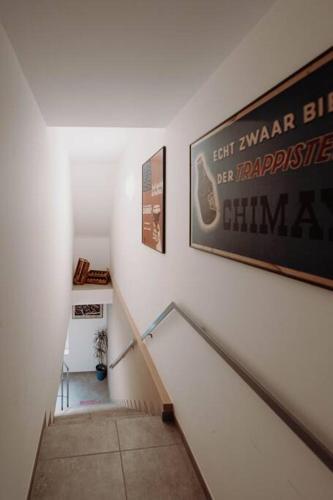 a hallway with a staircase with a painting on the wall at Chimay : La Grande Réserve in Chimay