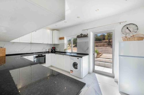 a kitchen with white appliances and a clock on the wall at Casa Emella Luxury Villa Albufeira in Albufeira