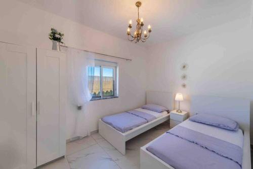 a bedroom with two beds and a window and a chandelier at Casa Emella Luxury Villa Albufeira in Albufeira