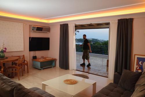 a man standing in a living room with a large window at Best view in the Bay! in Athens