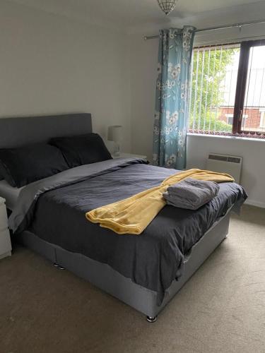 a bedroom with a bed with a yellow blanket on it at Spencer Court in Hornchurch