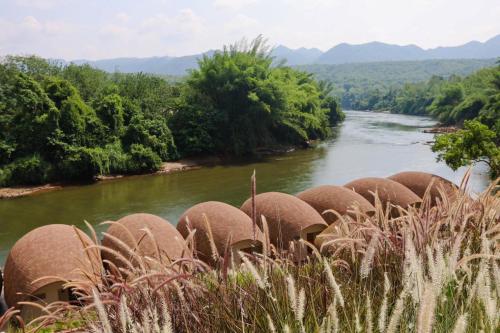 a herd of elephants walking along a river at VeeVaree Riverkwai Resort in Ban Kaeng Raboet