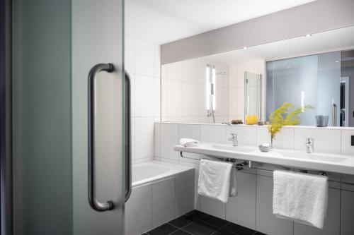 a bathroom with two sinks and a tub and a mirror at Boutique Hotel Bellevue Lermoos in Lermoos