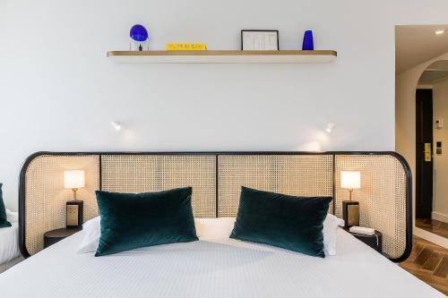 a bedroom with a large bed with green pillows at Hotel Le Friedland in Paris