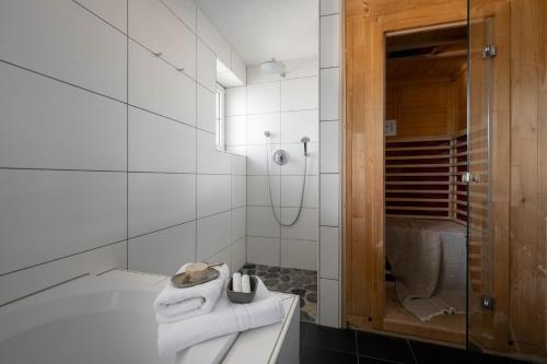 a white bathroom with a tub and a shower at Boutique Hotel Bellevue Lermoos in Lermoos