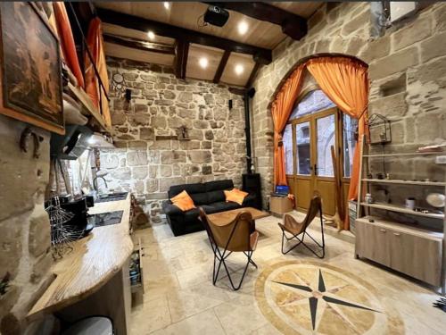 - un salon avec un canapé et un mur en pierre dans l'établissement Cassiopée, à Figeac
