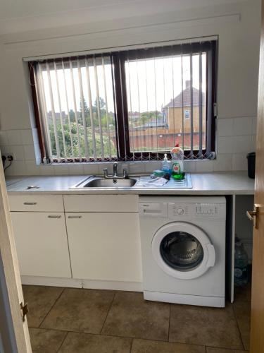 a kitchen with a sink and a washing machine at Spencer Court in Hornchurch