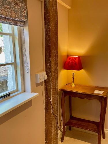 a lamp on a table next to a window at The Grannery in Wadhurst