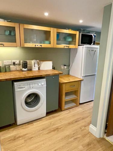 a kitchen with a washing machine and a refrigerator at The Grannery in Wadhurst