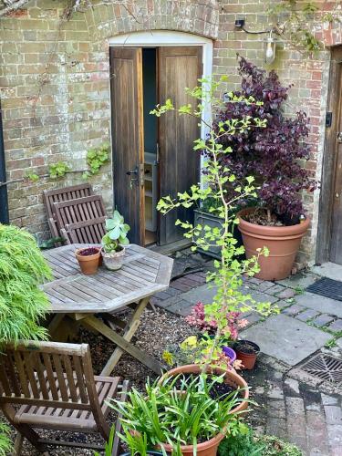 a patio with a table and chairs and plants at The Grannery in Wadhurst