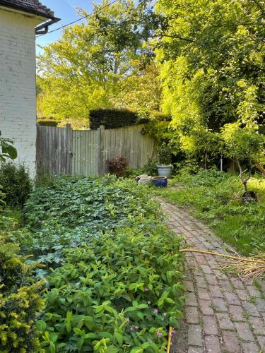 a garden with a brick path in front of a fence at The Grannery in Wadhurst