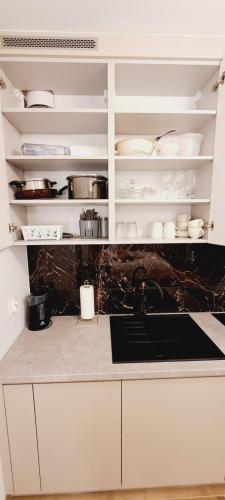 a kitchen with white cabinets and dishes on the shelves at AJP Gold Szczecin Dąbie in Szczecin