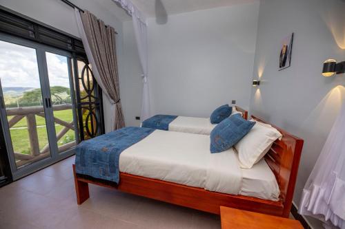 sypialnia z łóżkiem i dużym oknem w obiekcie The Kraal w mieście Mbarara