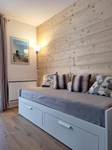 une chambre avec un grand lit avec un mur en bois dans l'établissement Studio Les 3 Lys Auron, à Auron