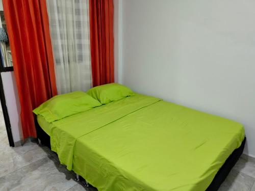 ein Bett mit grünen Laken in einem Zimmer in der Unterkunft Roshan in Cali
