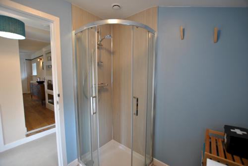 a shower with a glass door in a bathroom at Carpenters Cottage- coastal stay with garden in Pittenweem