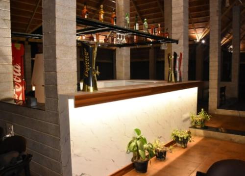 a bar with potted plants on a wooden floor at Nijaguna Residency in Chāmrājnagar