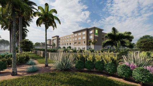 a hotel with palm trees and plants in a garden at Holiday Inn Express Cape Canaveral, an IHG Hotel in Cape Canaveral