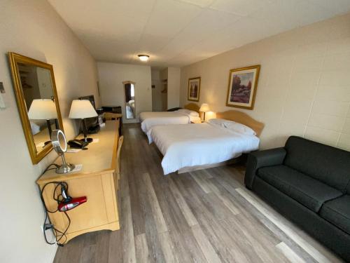 a hotel room with two beds and a couch at Motel Panoramique in Saguenay