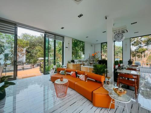 a living room with an orange couch and a table at VeeVaree Riverkwai Resort in Ban Kaeng Raboet
