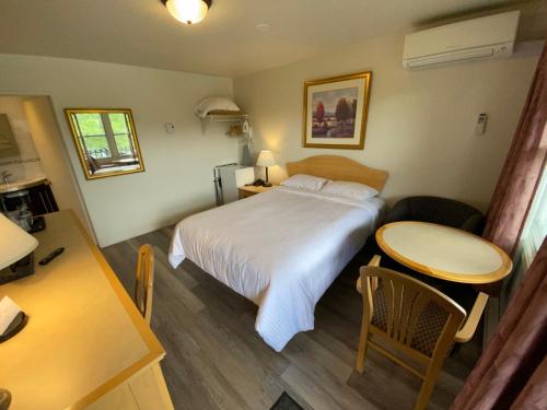 a hotel room with a bed and a table at Motel Panoramique in Saguenay