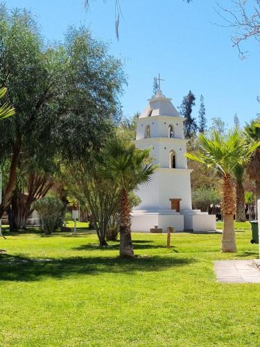 a building in a park with palm trees at Cabañas La Huayca - Caja Los Andes in Pica
