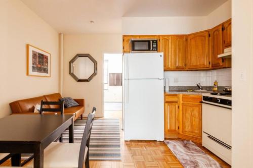une cuisine avec une table et un réfrigérateur blanc dans l'établissement ✪ Large 2 Bedrooms ✪ Queen Beds ✪ Work Stations, à New York