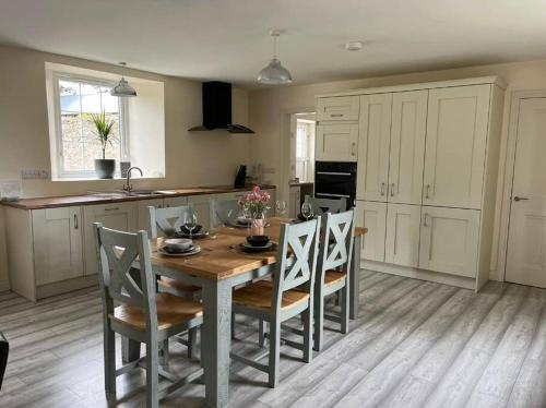 una cocina con mesa de madera y sillas y una cocina con armarios blancos. en Dundonagh House, Glaslough, en Monaghan