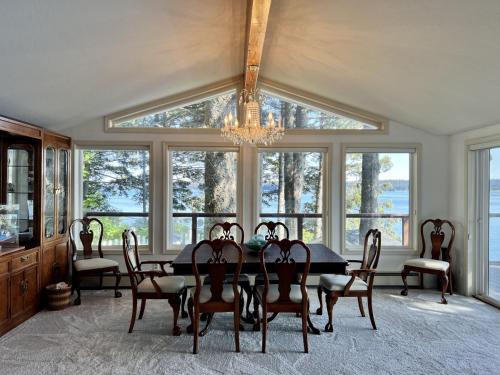 een eetkamer met een tafel, stoelen en ramen bij The Main Deck Cliffside Ocean Views in Kodiak