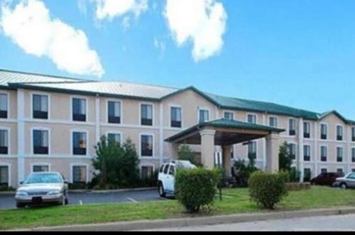 un gran edificio con coches estacionados en un estacionamiento en Ark Suites, en Jonesboro