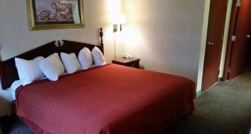 Pokój z czerwonym łóżkiem i białymi poduszkami w obiekcie Ark Suites w mieście Jonesboro