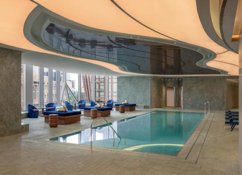 una piscina en el vestíbulo del hotel con sillas azules en W Macau - Studio City, en Macau