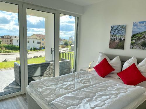 ein Bett mit roten Kissen in einem Schlafzimmer mit Balkon in der Unterkunft Ferienappartement Balve in Sassnitz